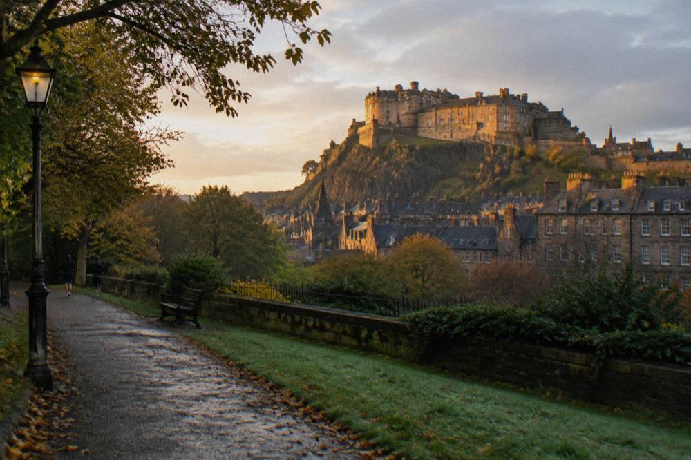 Edinburgh Castle on its rock seen from gardens below at golden hour