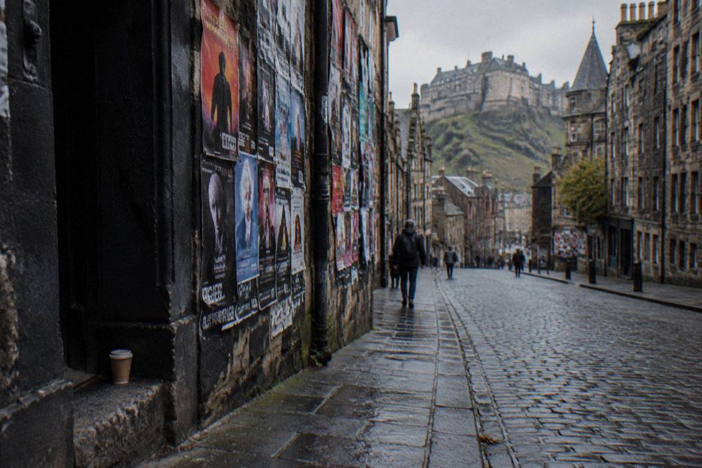 Cobbled Edinburgh close with festival posters displayed on old stone walls