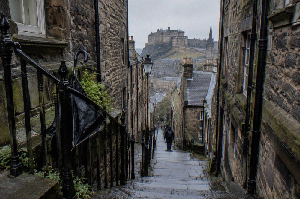 Narrow stone close rising between tall Old Town tenement buildings in Edinburgh