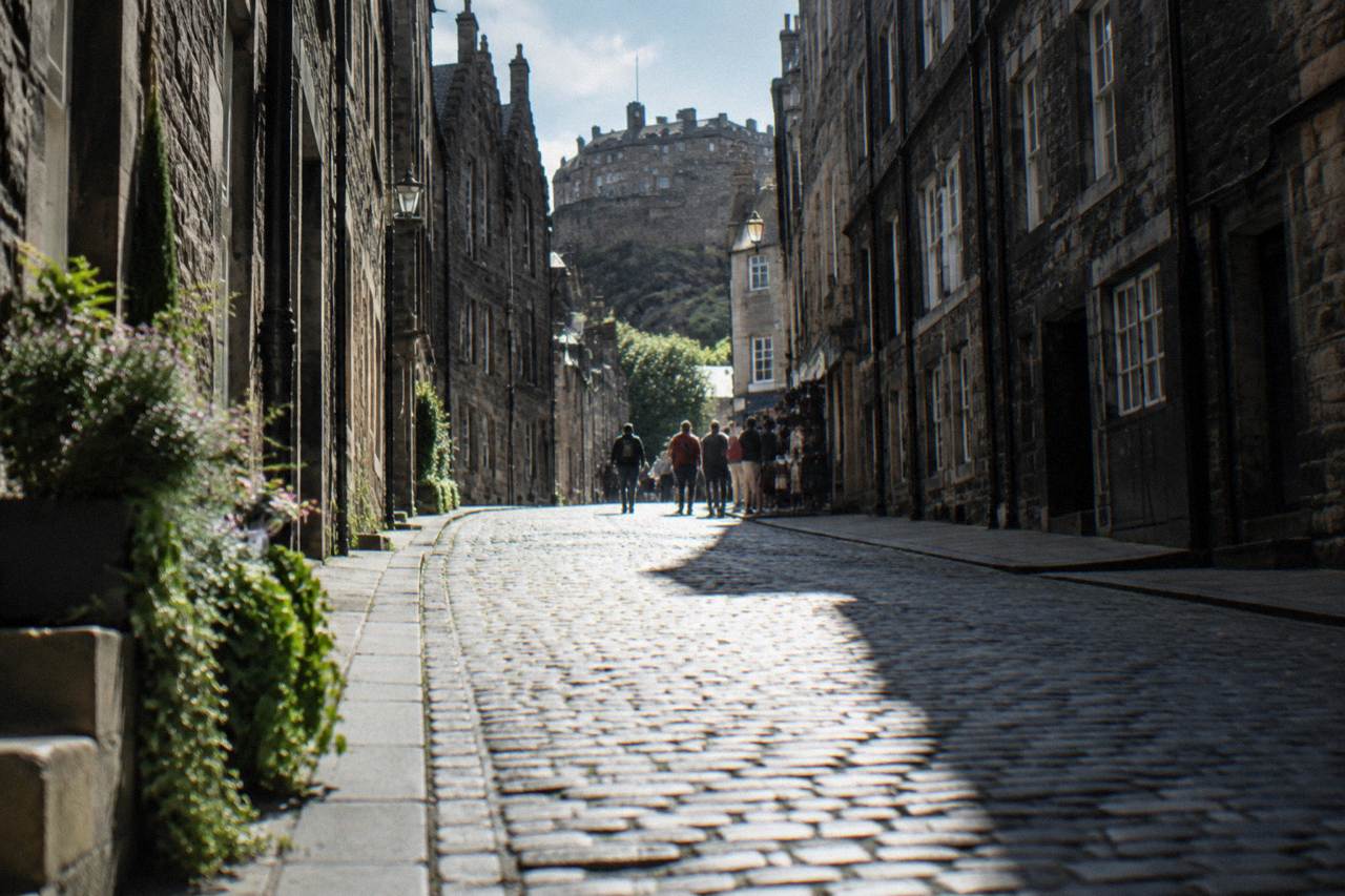 Cobbled Edinburgh Old Town street with tall stone tenement buildings rising on either side