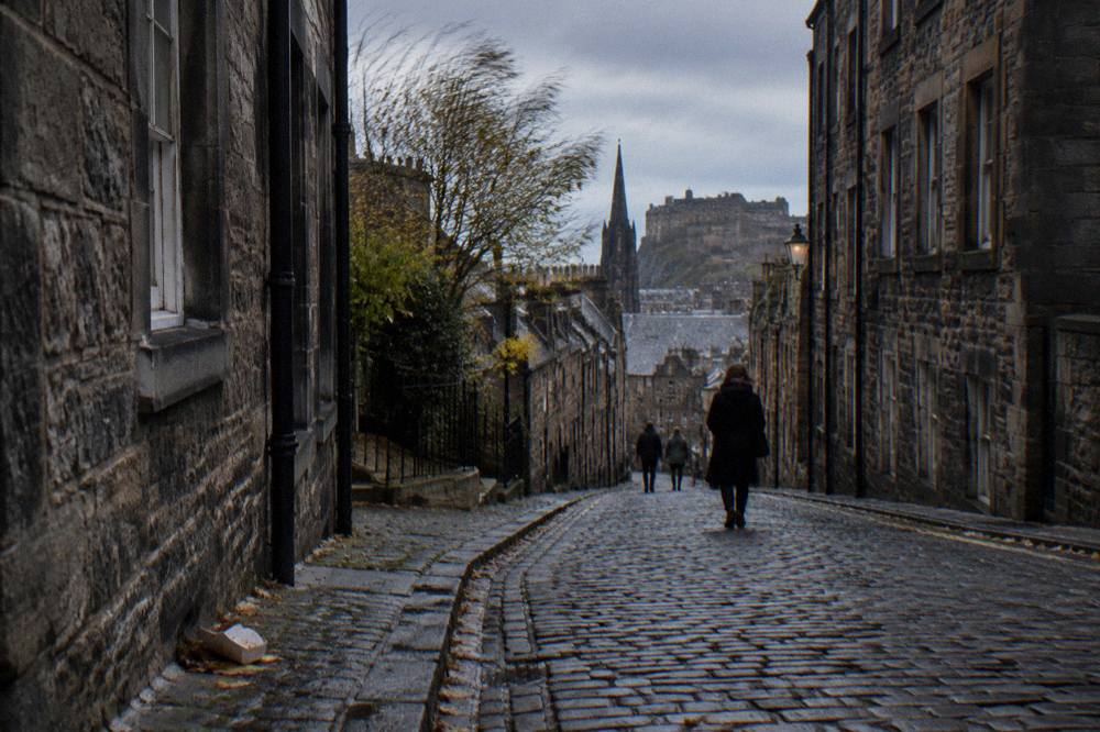 Narrow cobbled street in Edinburgh Old Town lined with old stone buildings
