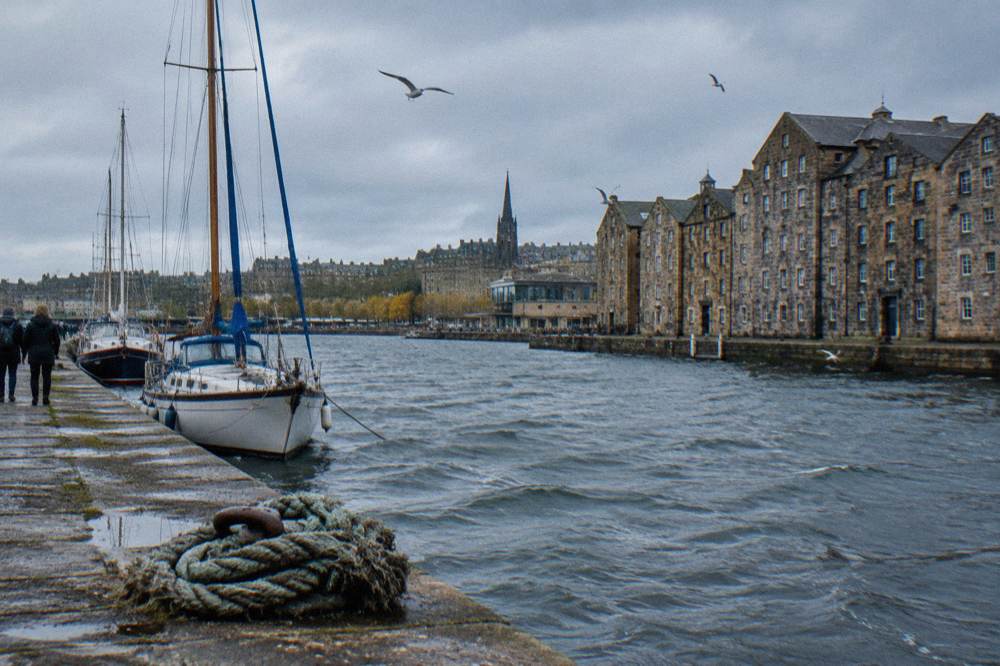 Leith waterfront quay with masted boats moored beside converted stone warehouses