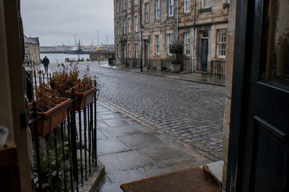 Cobbled Edinburgh street with historic tenement buildings and window boxes