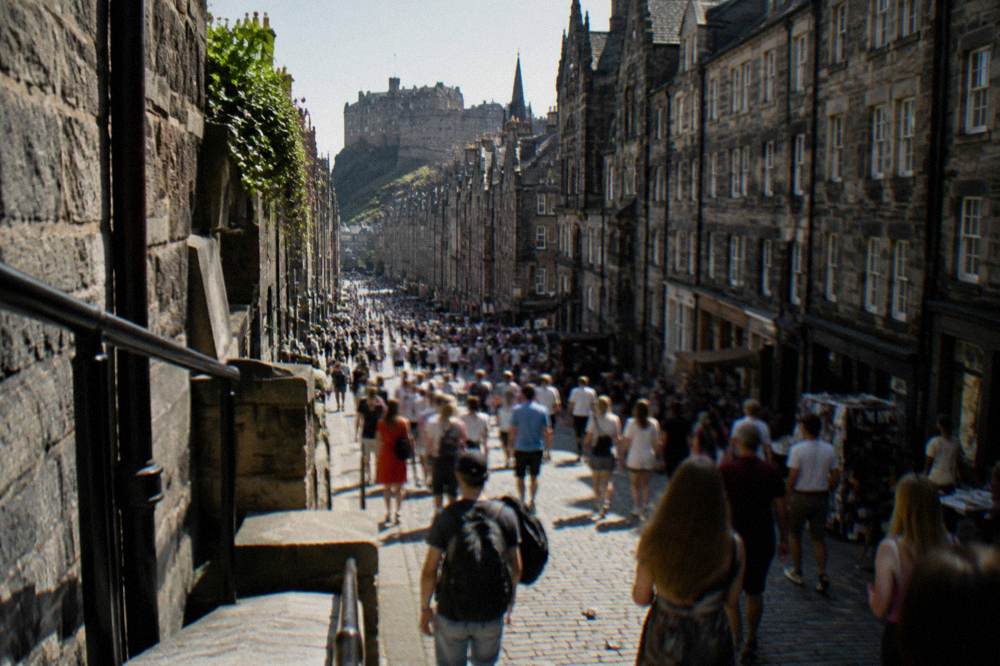 Crowded festival street with banners and temporary venue signage in August