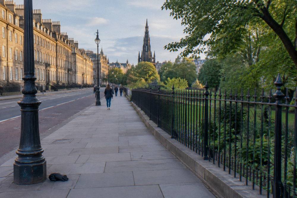 Broad Georgian street in Edinburgh New Town with wide pavements beside a garden square
