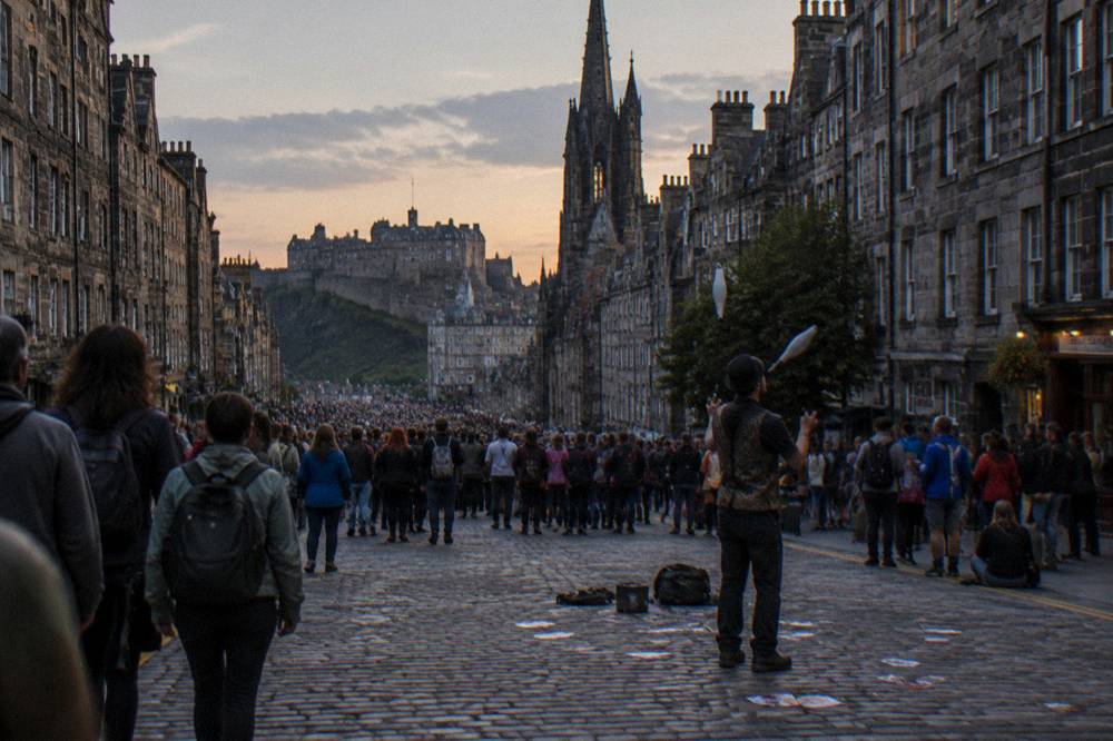 Crowded festival street with performers and visitors in Edinburgh Old Town