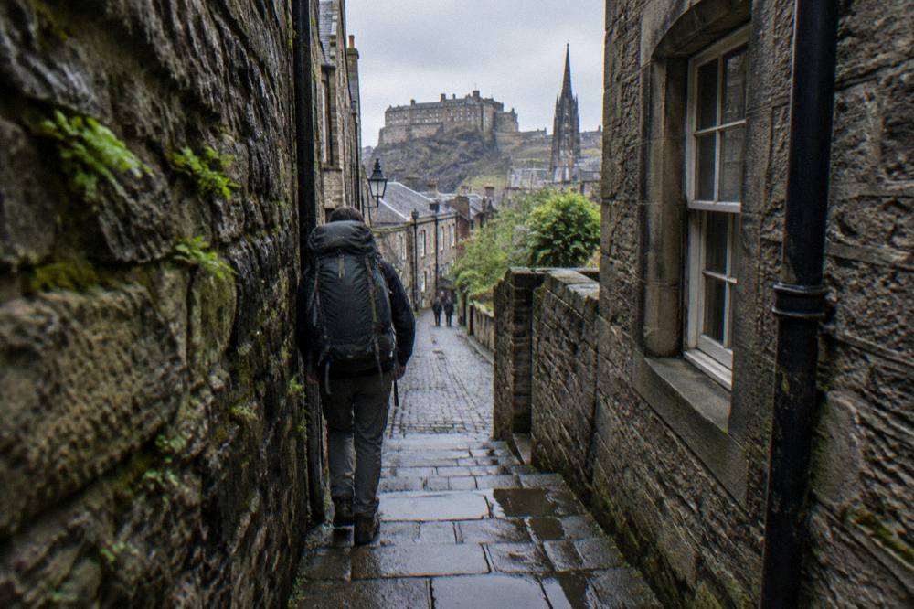 Backpacker with rucksack walking along a stone close in Edinburgh