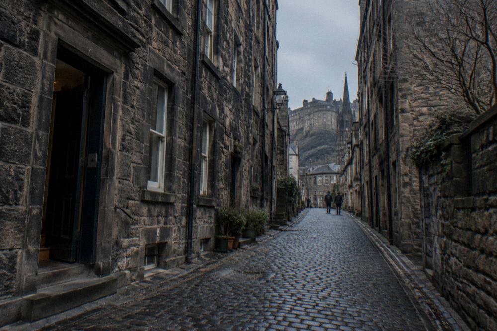 Narrow cobbled alley between tall stone buildings in Edinburgh Old Town