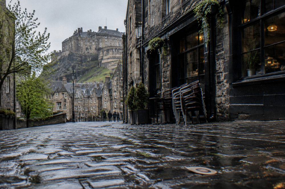 Historic street with pubs and stone facades in the Grassmarket area below the castle
