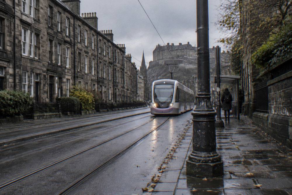 Tram travelling along a west Edinburgh street toward the city centre