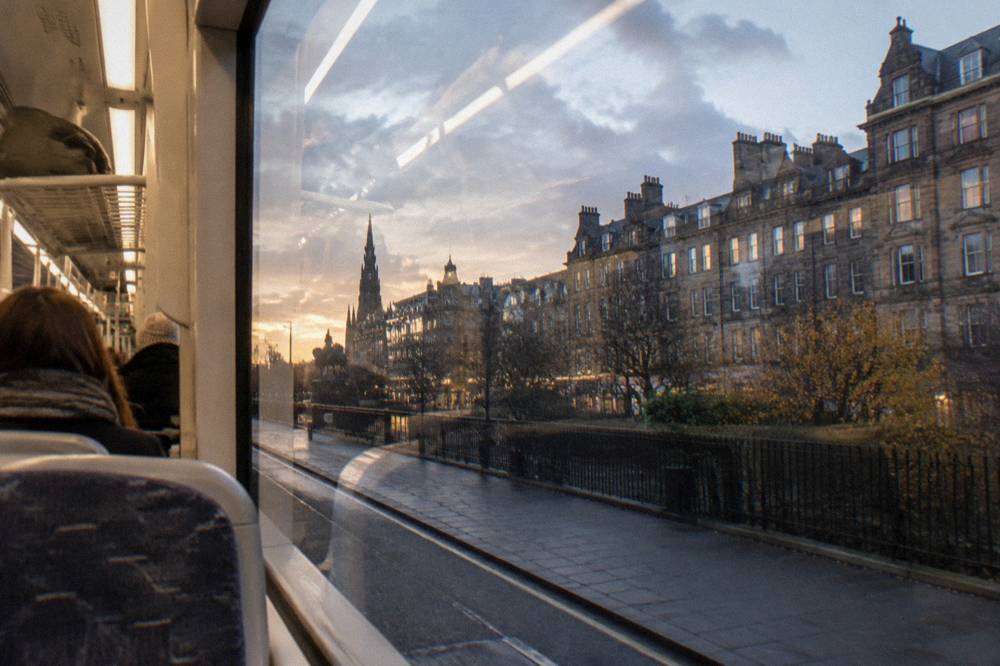 Interior of a modern Edinburgh tram with seated passengers and luggage racks