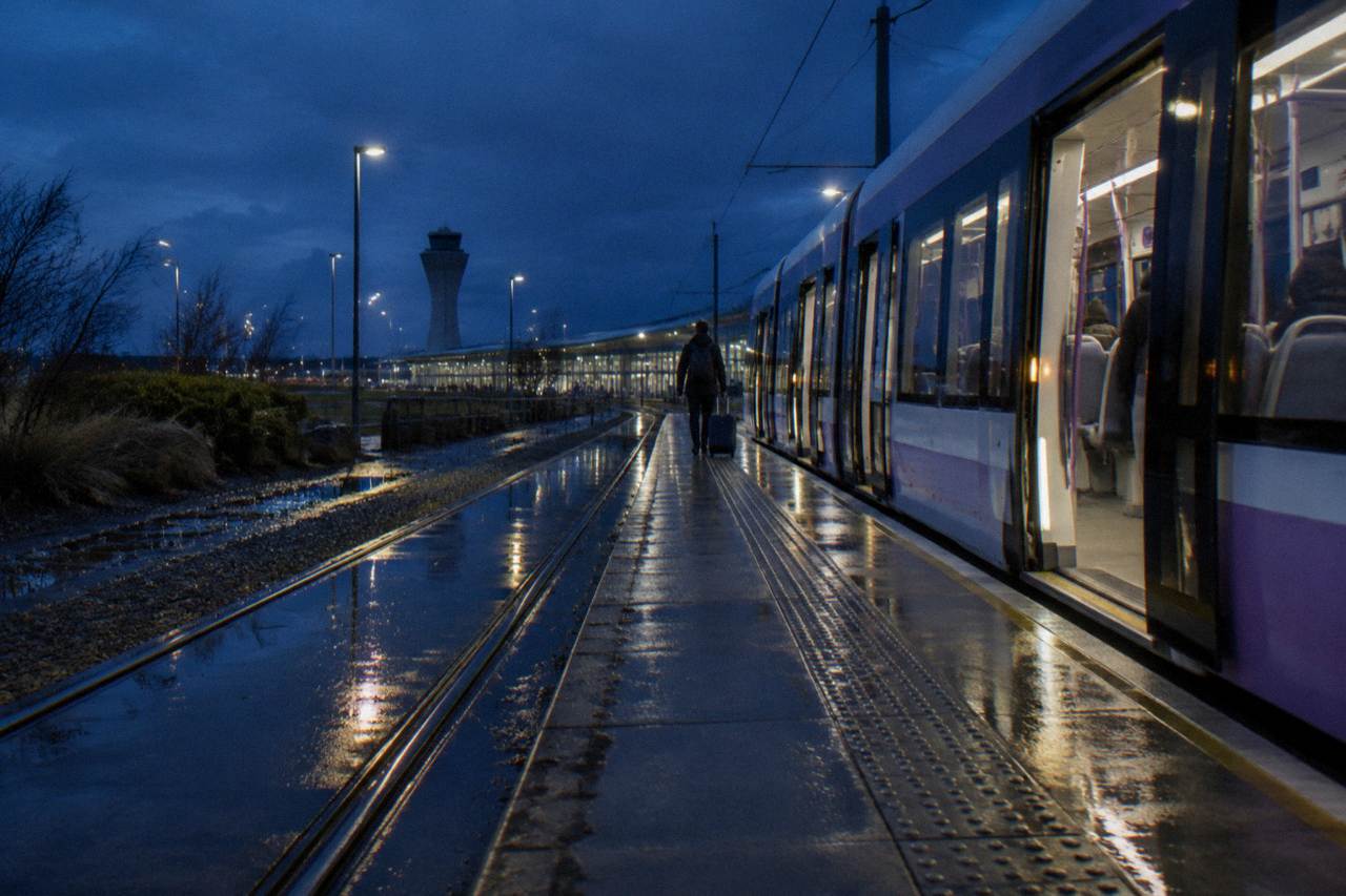 Edinburgh tram waiting at a stop beside a modern terminal building at dusk