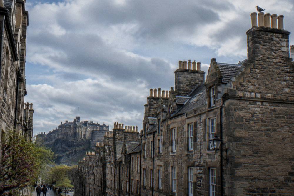 Row of traditional stone tenement flats with chimneys against a grey sky