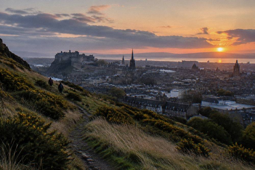 Hikers on a grassy ridge path above Edinburgh's Old City skyline