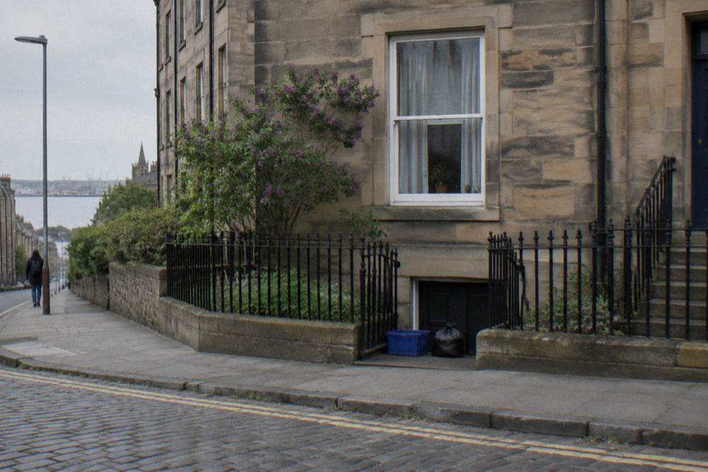 Exterior of a stone building with sash window, iron railings and cobbled street