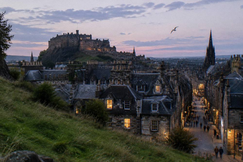 Evening view of Edinburgh rooftops from a hill with the castle silhouette in the distance